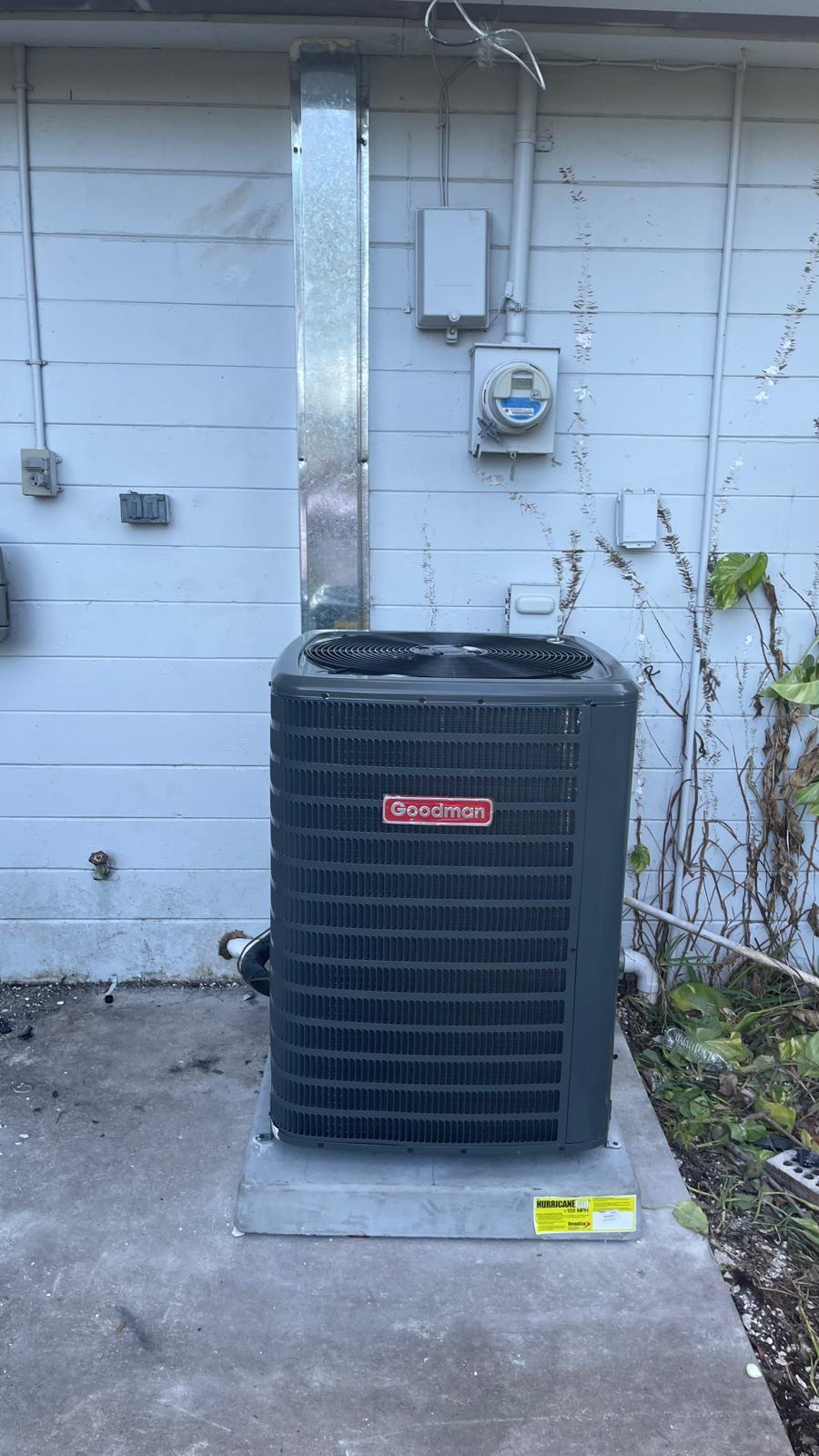 New Goodman AC condenser installation on hurricane pad in a Florida home