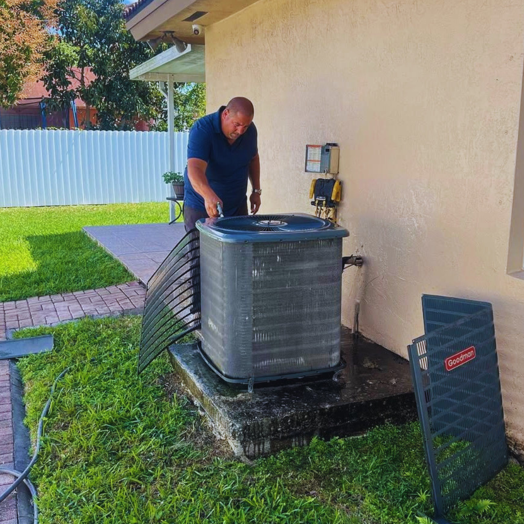 HVAC technician performing AC maintenance on a Goodman condenser in Florida